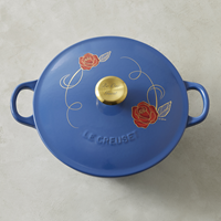 The Beauty and the Beast Soup Pot by Le Creuset is made in France, features a hand-applied red rose-and-vine appliqué design on lid and a stainless-steel knob with gold metallic finish engraved with 