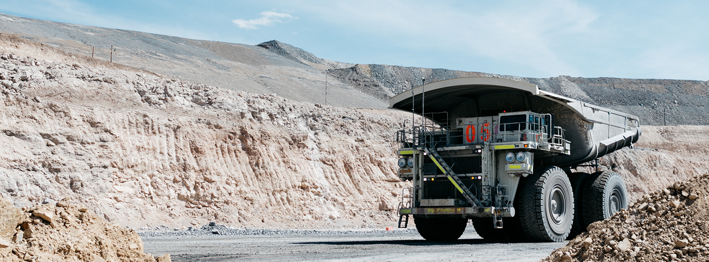 A worker in prtective gear handles molten material outside of a large furnace.