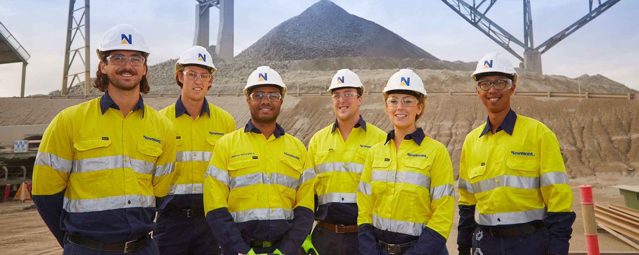 Two happy miners pose in a cave, holding their work gear.