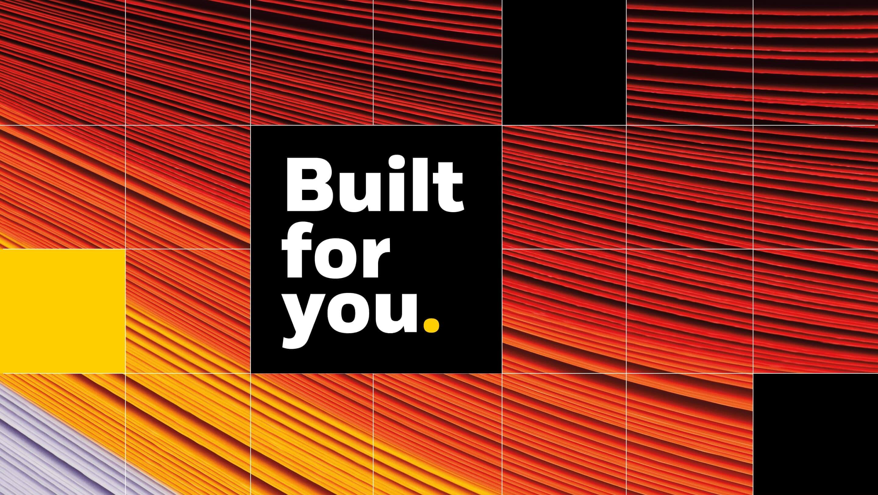 A full screen image shows layers of coloured paper with non-uniform spacing. Overlaid is a 7 by 4 grid, some of the squares have a solid color. In the center are the words 'Built for you.'